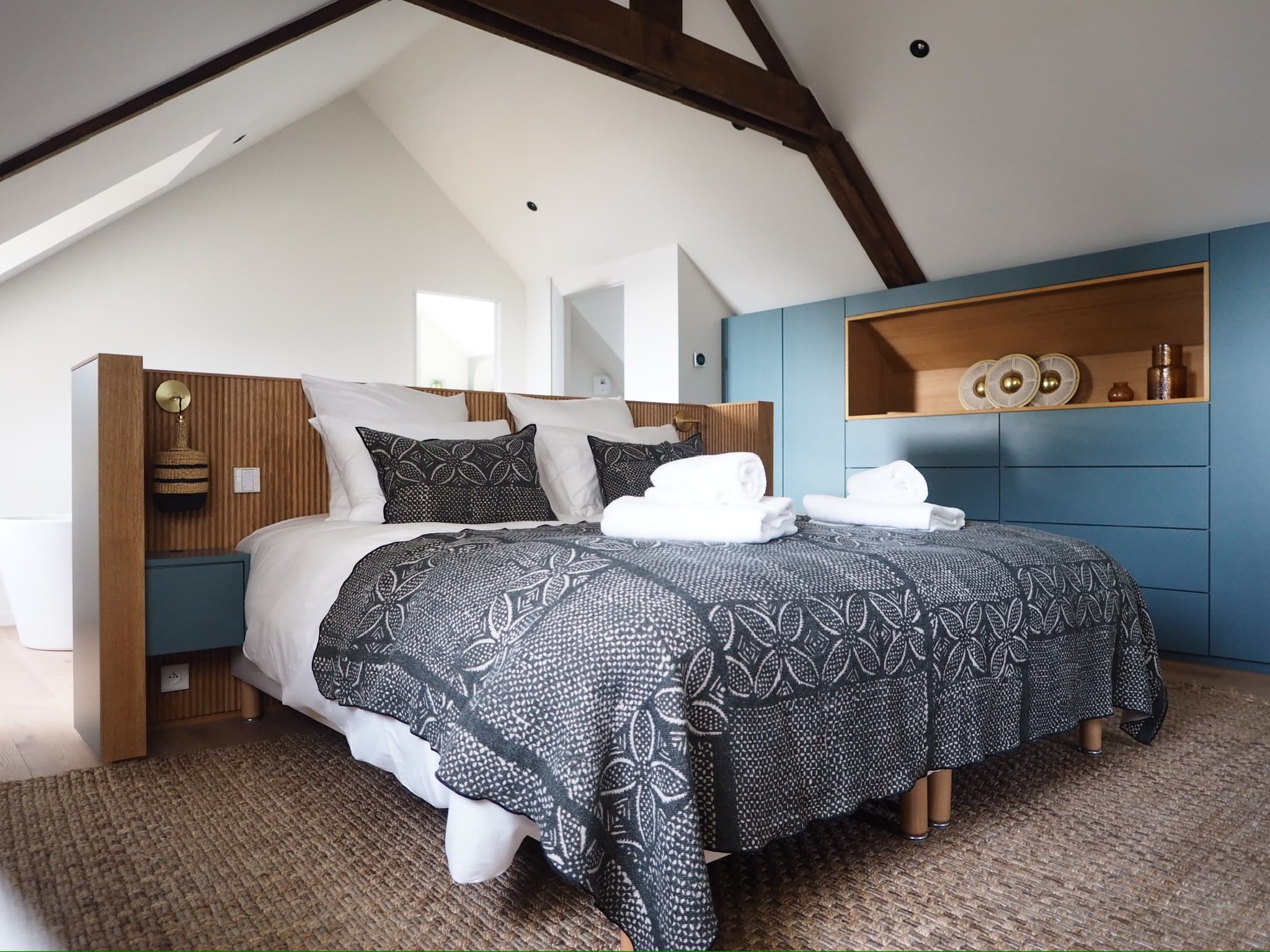 Chambre sous comble avec tête de lit ilot en chêne canelé et laque gris-bleu, linge de lit gris, poutres apparentes, projet Quiberon A4 Créations
