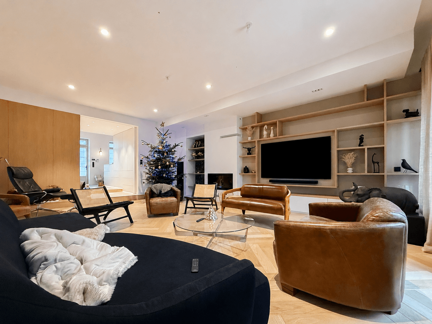 Salon avec meuble TV intégré en chêne et laque, étagères et canapés en cuir marron, parquet point de Hongrie, projet Port-Louis A4 Créations