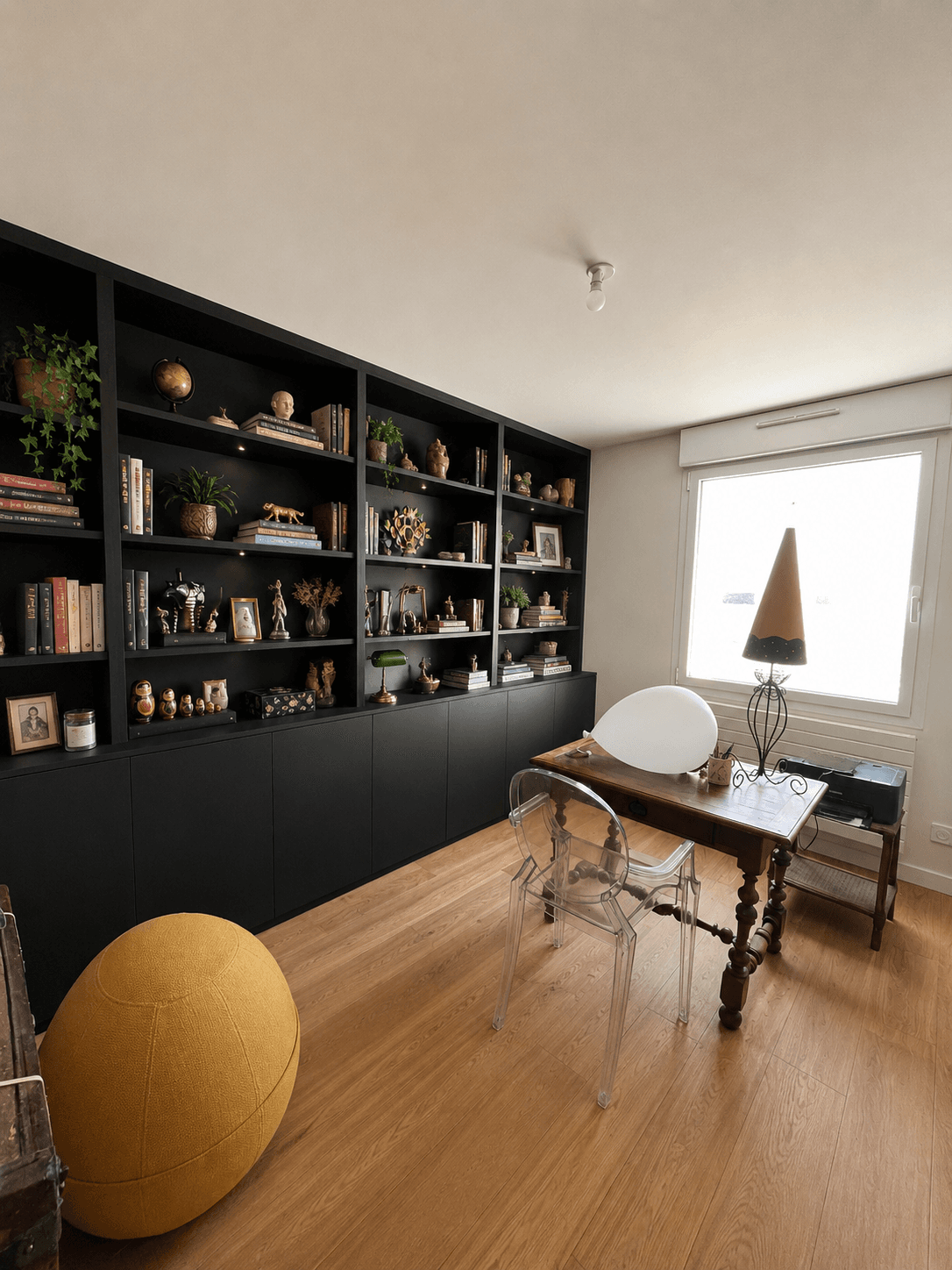 Bibliothèque intégrée noire avec livres et objets décoratifs, espace bureau avec parquet chêne clair, projet Larmor-Plage A4 Créations